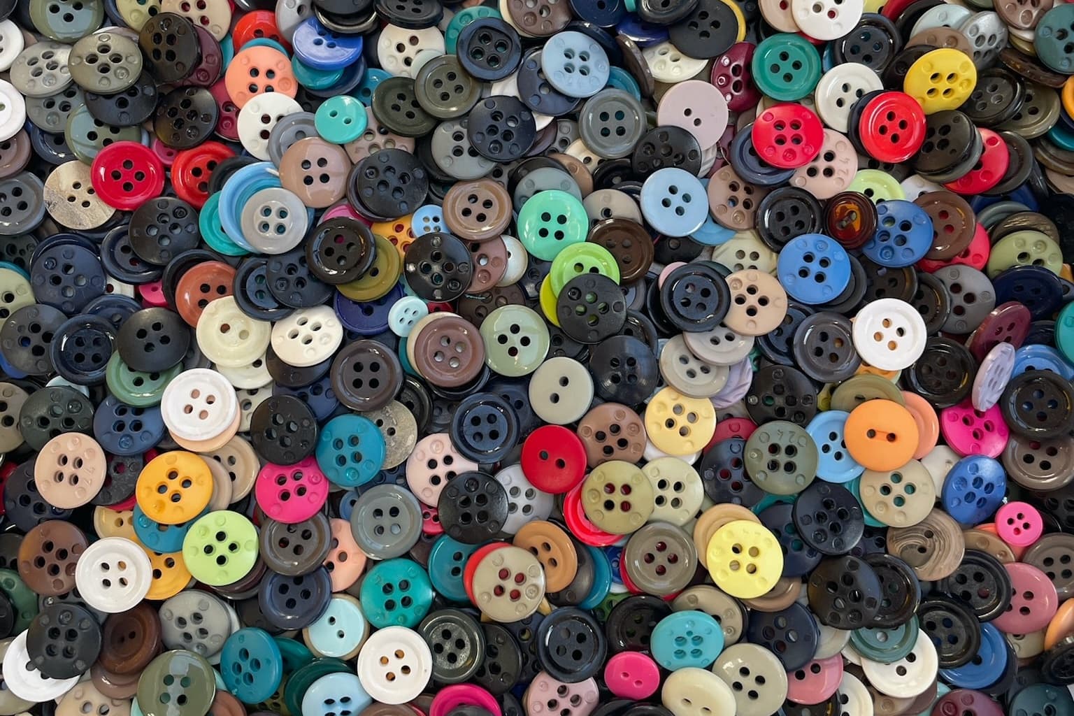 Un gros stock de boutons de différentes formes, tailles et couleurs dans des bacs en plastique empilés les uns sur les autres dans un atelier de confection