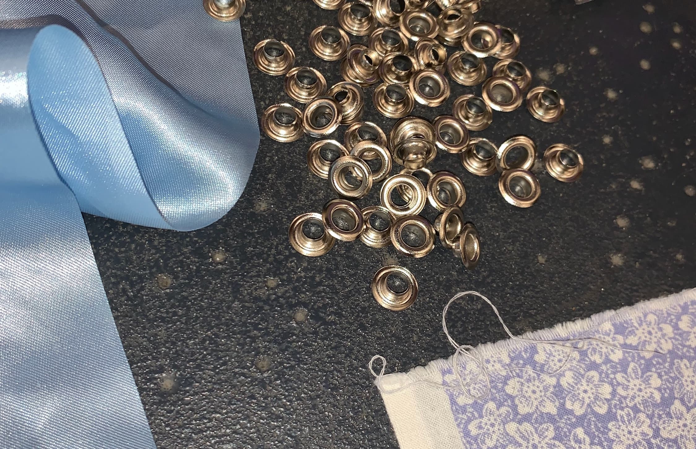 accessoires métalliques et coupon de tissus bleu brillant sur le plan de travail d'un atelier de confection